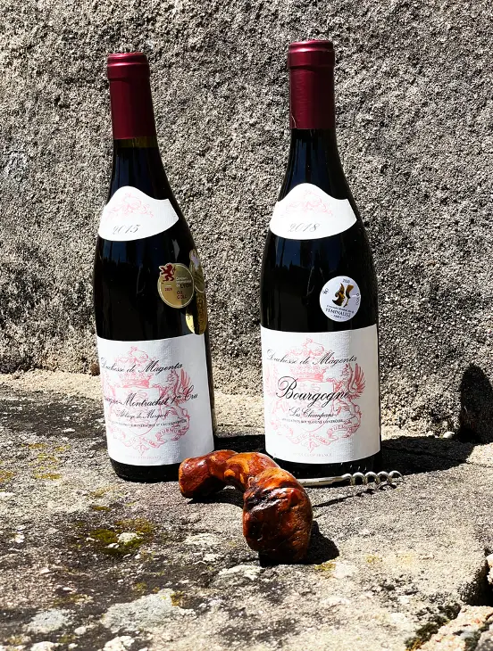 Flaschen Bourgogne Rouge Les Champans auf einer sonnenbeschienenen Steinmauer in Chassagne-Montrachet